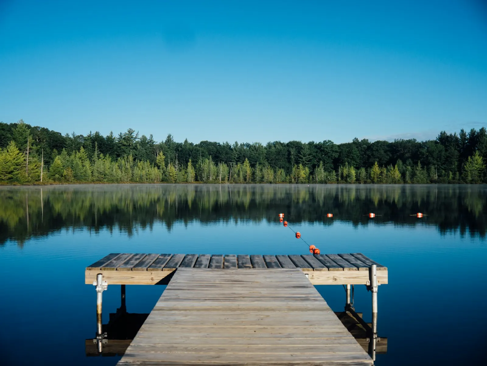 Calm North Idaho lake with a wooden dock at the treeline