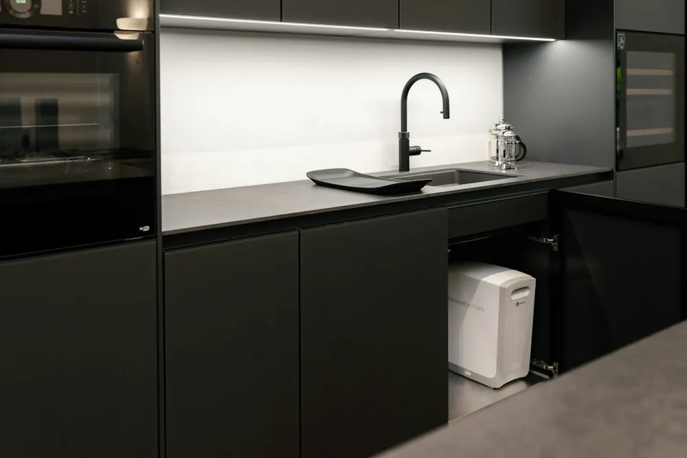Under-sink water filtration system installed in a kitchen cabinet