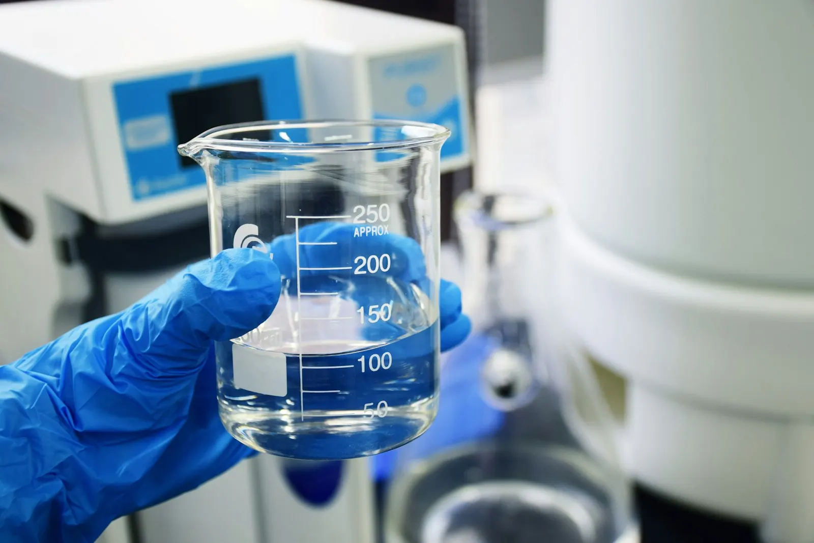 Gloved hand holding a beaker of water during on-site testing